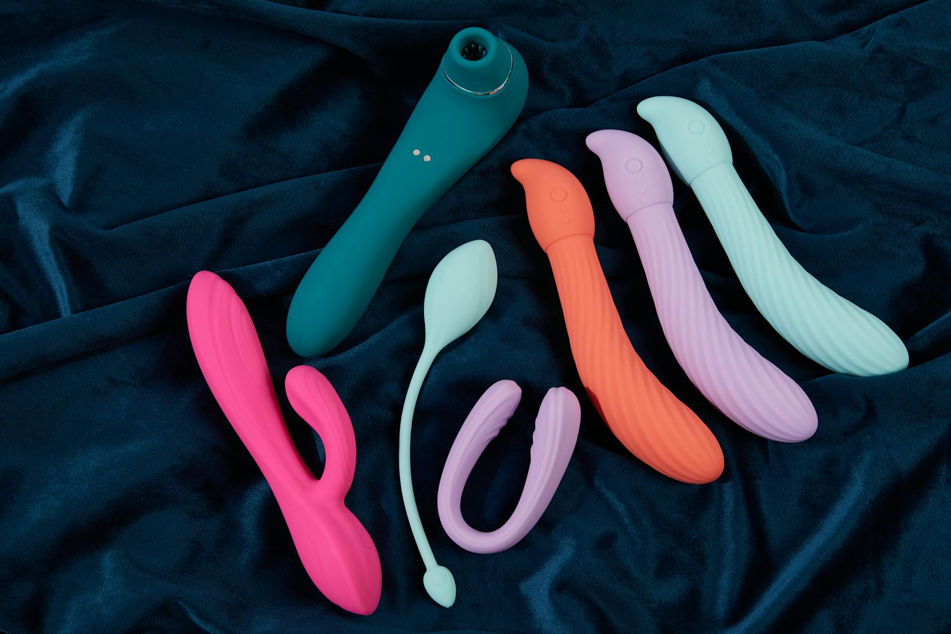 A vibrant collection of clitoral vibrators displayed on deep blue fabric, showcasing the range of options available from Hello Nancy.