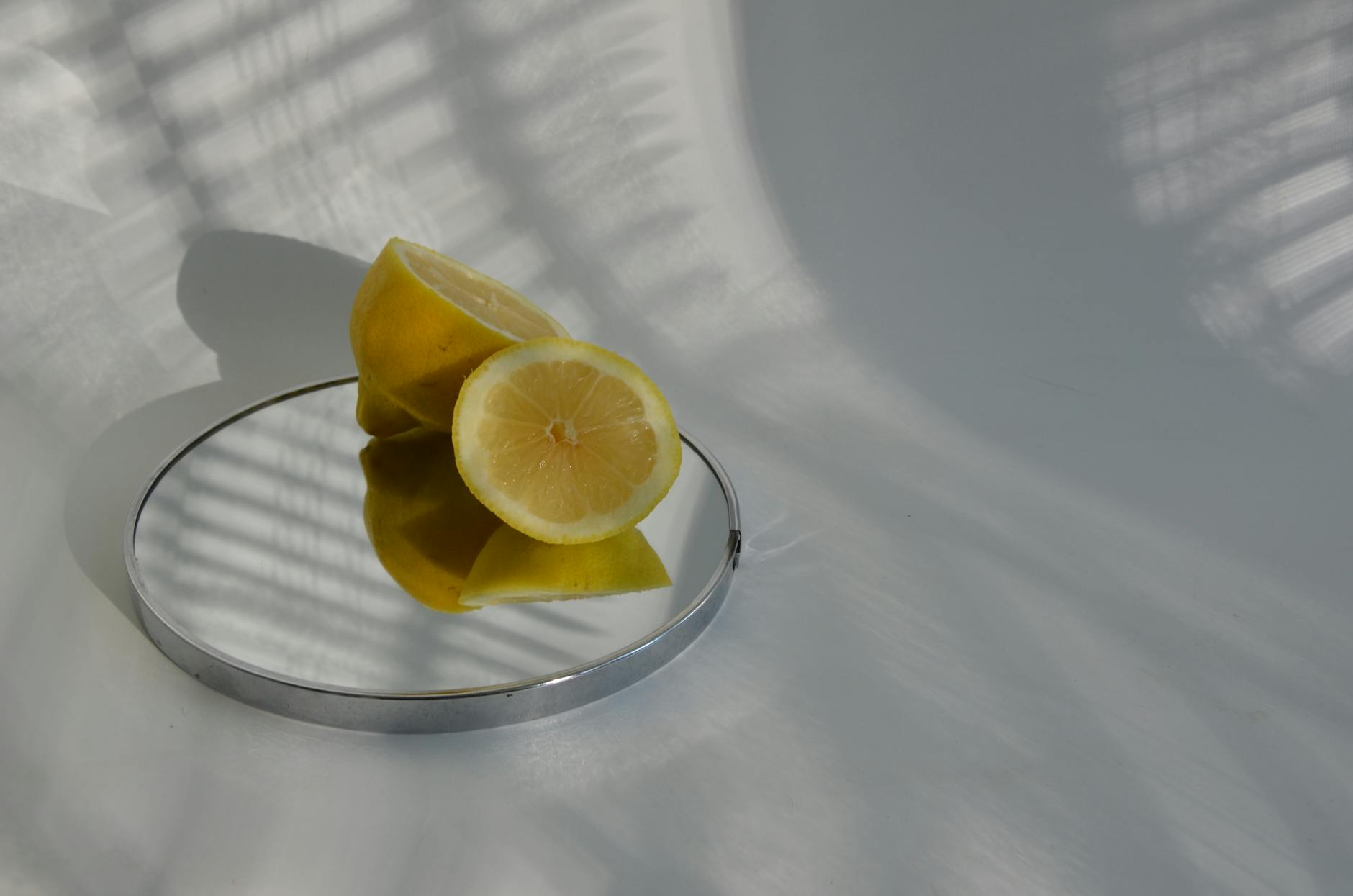 Limones cortados sobre un espejo con sombras, fotografía minimalista de alimentos