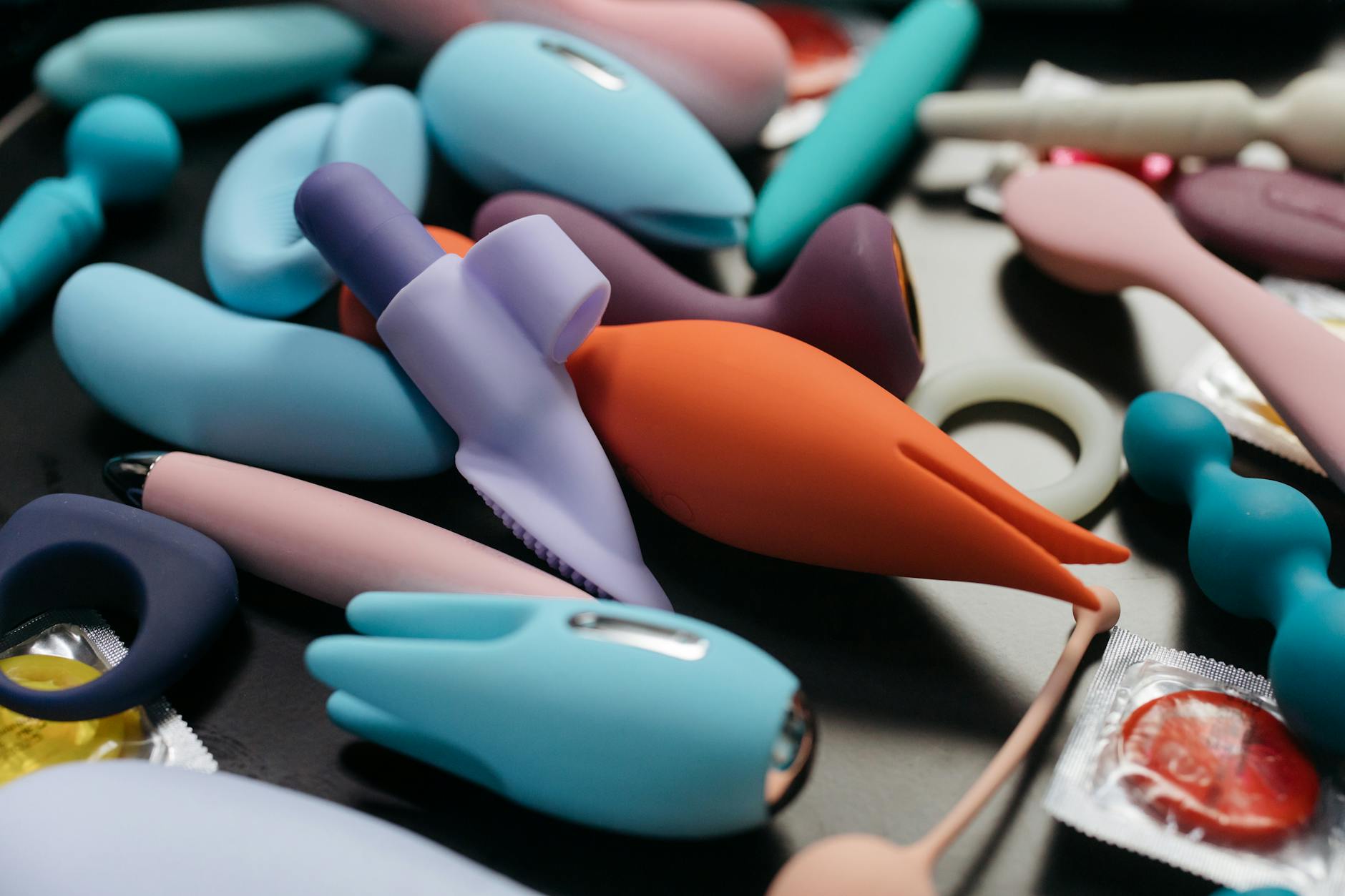 Una mano sosteniendo un vibrador naranja sobre un fondo púrpura minimalista